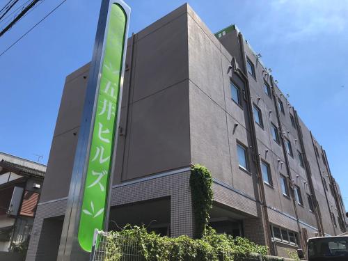 a building with a green sign in front of it at Business Hotel Goi Hills in Ichihara