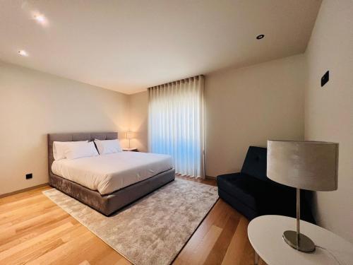 a bedroom with a bed and a table and a lamp at Morgado Granja Luxury Suits in Aveiro