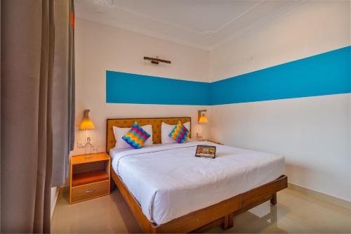 a bedroom with a bed with a blue wall at goSTOPS Mcleodganj Dalailama Temple in Dharmsala