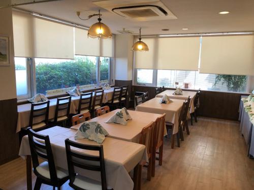 a dining room with tables and chairs and windows at Business Hotel Goi Hills in Ichihara