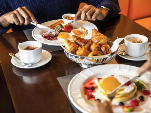 a table topped with plates of breakfast foods and coffee at ibis Deira Creekside Dubai in Dubai