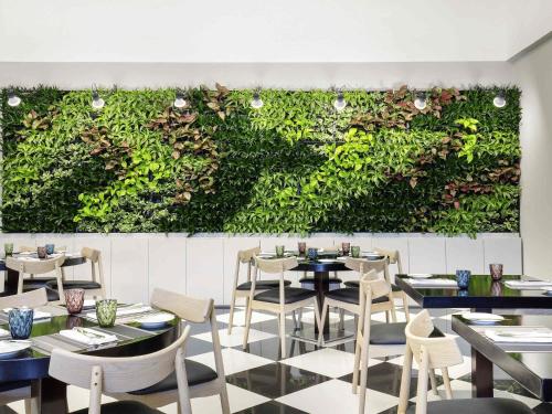 a restaurant with tables and chairs and a green wall at ibis Deira Creekside Dubai in Dubai
