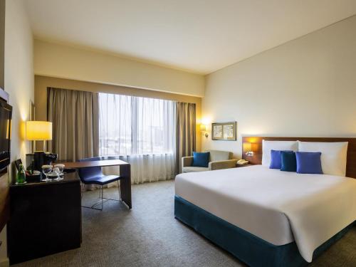 a hotel room with a large bed and a desk at Novotel Deira Creekside Dubai in Dubai