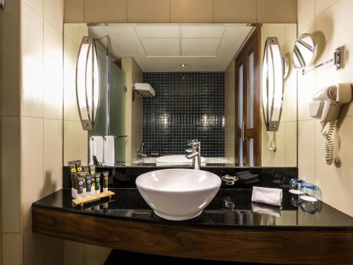 a bathroom with a sink and a large mirror at Novotel Deira Creekside Dubai in Dubai