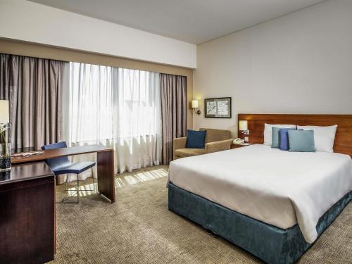 a hotel room with a large bed and a desk at Novotel Deira Creekside Dubai in Dubai