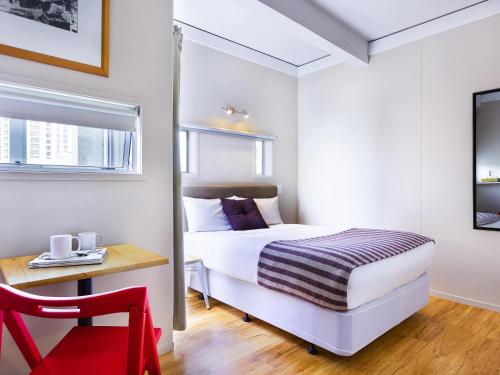 a bedroom with a bed and a desk and a red chair at ibis budget Auckland Central in Auckland