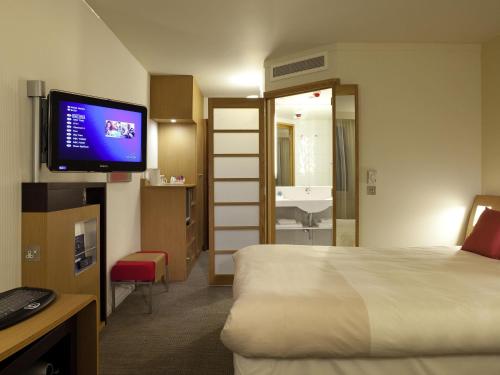 a hotel room with a bed and a flat screen tv at Novotel Liverpool Centre in Liverpool