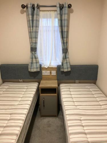 two beds in a small room with a window at Rejuven8 Rentals - Kingfisher Caravan Park - Ingoldmells in Ingoldmells