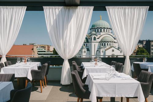 a restaurant with white tables and chairs and a building at CRYSTAL Hotel Belgrade in Belgrade