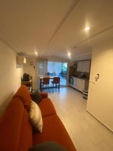 a living room with an orange couch and a kitchen at Studio Smart&Cosy in Porto-Vecchio