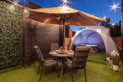 a table and chairs under an umbrella in a yard at 5BR - House - Hot Tube - Airport - A38-A50 - Parking in Burton upon Trent