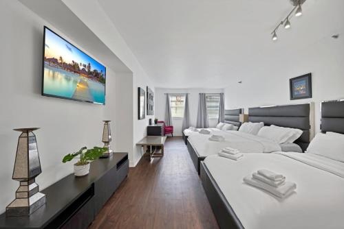 Una habitación blanca con dos camas y un sofá. en Casa Grande Suites on Ocean Drive, en Miami Beach