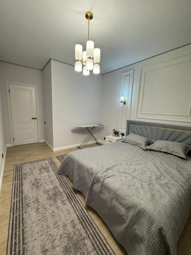 a bedroom with a bed with a rug and a chandelier at Stylish apartment & Perfect choice for Travellers in Almaty