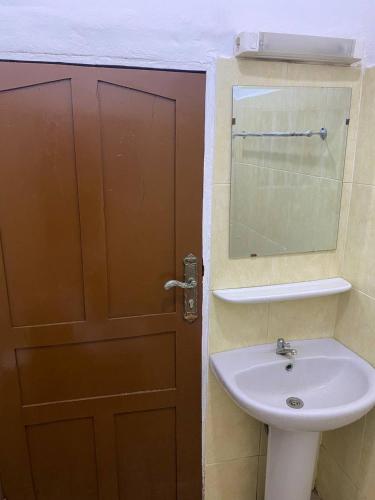 a bathroom with a sink and a door with a mirror at Maison Calme, Chambre Privée Calavi in Abomey-Calavi
