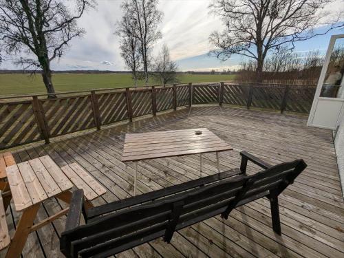 a wooden deck with a bench and a table at OGO781-Mjoelby-Norrby-Naesloesegard-1 in Mjölby