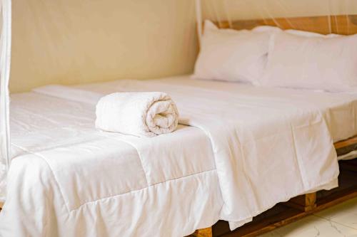 - un lit avec des draps blancs et une serviette dans l'établissement Culture House - Heritage Stay with Family Comforts, à Gulu