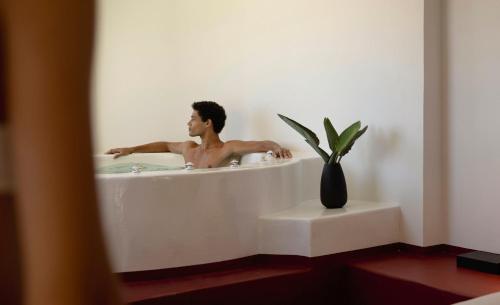 a man is in a bath tub with a vase at Neema Maison Finikia Santorini in Oia