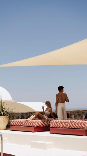 a group of people sitting on the edge of a beach at Neema Maison Finikia Santorini in Oia