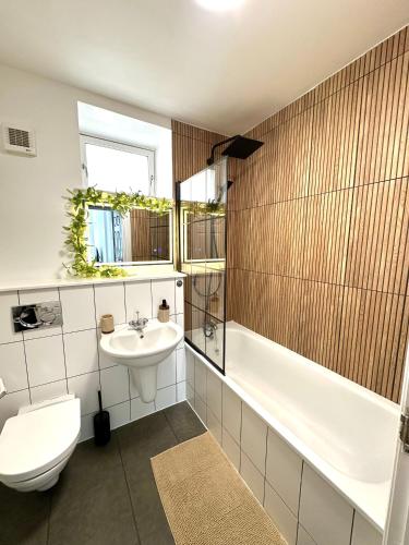 a bathroom with a toilet and a sink and a tub at The Tay Residence, City Centre in Perth