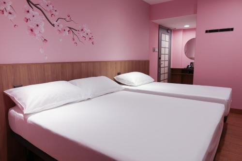 a bedroom with a large white bed with pink walls at Hotel Sakura by Venue in Singapore