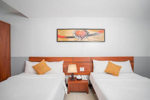 a bedroom with two beds and a table with a lamp at Quoc Cuong Hotel & Apartment Danang by Haviland in Da Nang