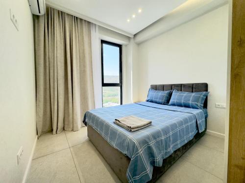 a bedroom with a bed with blue sheets and a window at GSS - 2 Bedroom Apartment in Tbilisi City