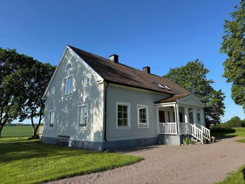 a small white house with a porch on a field at OGO780-Mjoelby-Norrby-Naesloesegard-1 in Mjölby
