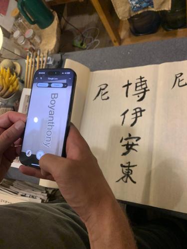 a person holding a cell phone in front of a book at Zhangjiajie One Art Guesthouse in Zhangjiajie