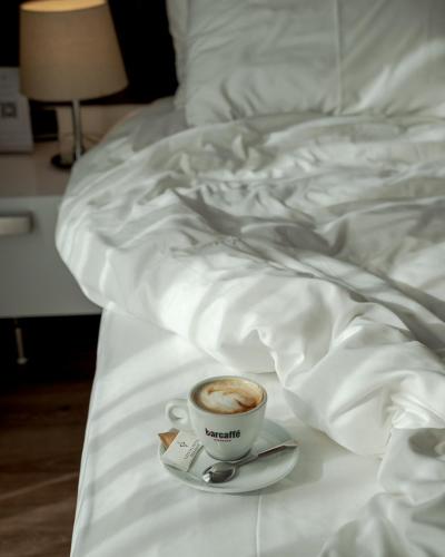 a cup of coffee on a plate on a bed at CRYSTAL Hotel Belgrade in Belgrade