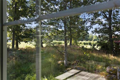 a window view of a field with a wooden bench at KRO043-Urshult-Vaesterbotorp-Bosgard in Urshult
