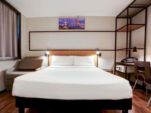 a bedroom with a large white bed and a chair at ibis Copacabana Posto 2 in Rio de Janeiro