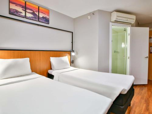 two beds in a hotel room with white sheets at ibis Copacabana Posto 2 in Rio de Janeiro