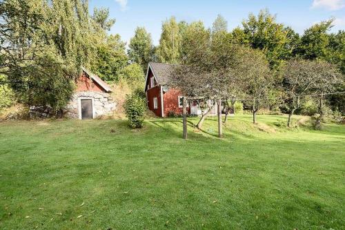 a red barn in a grassy field next to a house at KRO191-Aelmhult-Boastad-Lillstugan in Länshult
