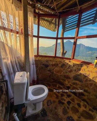 a bathroom with a toilet and a window at prince's place cabins and camping in Badulla