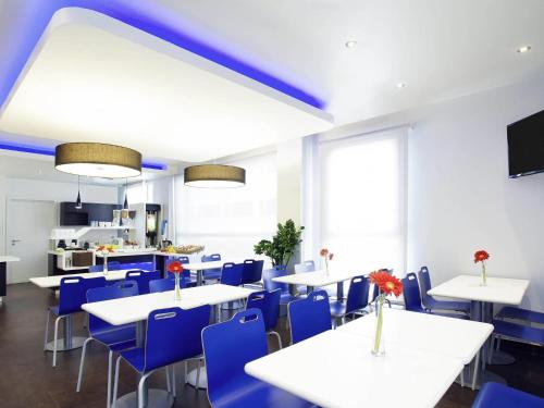 a dining room with white tables and blue chairs at Ibis Budget Madrid Centro Las Ventas in Madrid