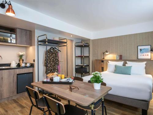 a hotel room with a bed and a table at Novotel Suites Nice Airport in Nice