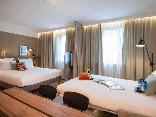 a hotel room with two beds and a table at Novotel Suites Nice Airport in Nice