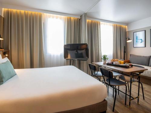 a hotel room with a large bed and a desk at Novotel Suites Nice Airport in Nice
