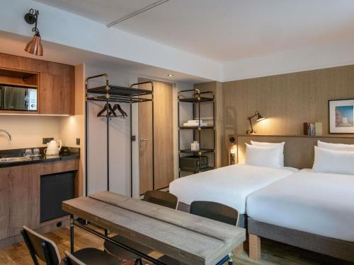 a hotel room with two beds and a table at Novotel Suites Nice Airport in Nice