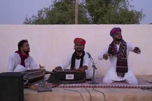 a group of three men sitting next to a microphone at Royal Gadhvi Desert Camp in Sām