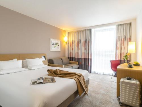 a hotel room with a bed with a book on it at Novotel Edinburgh Park in Edinburgh