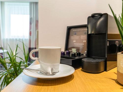 a coffee cup on a table next to a computer at Novotel Edinburgh Park in Edinburgh