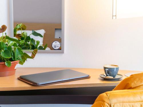 a laptop on a table with a cup of coffee at Novotel Edinburgh Park in Edinburgh