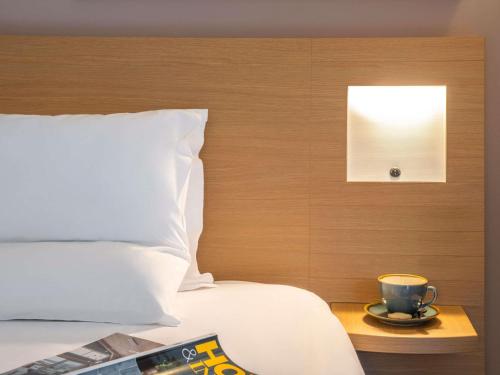 a bed with a cup of coffee on a table at Novotel Edinburgh Park in Edinburgh