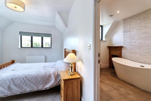 a bedroom with a bed and a bath tub at Beautiful arts and crafts home in East Grinstead