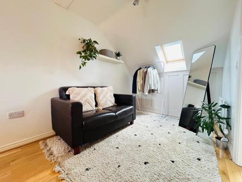a living room with a black leather couch and a mirror at Durham City Centre 5 bedroom House in Gilesgate