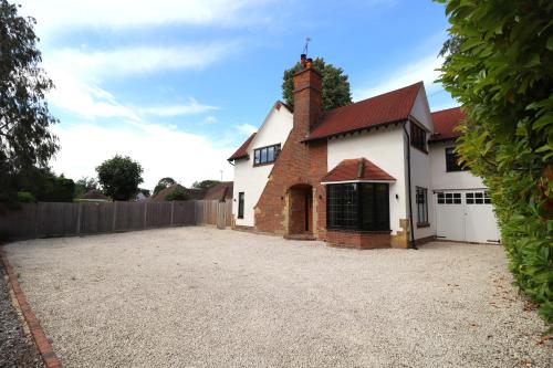 a large white house with a fence and a driveway at Beautiful arts and crafts home in East Grinstead