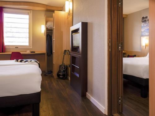 a hotel room with two beds and a closet at ibis Cannes Mandelieu in Mandelieu-la-Napoule