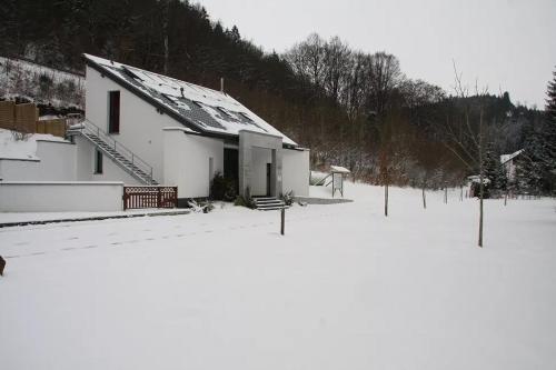 a white building with a snow covered roof in the snow at Studio comfort in Bischenrech