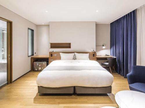 a bedroom with a large bed and a desk at Ibis Ambassador Suwon in Suwon